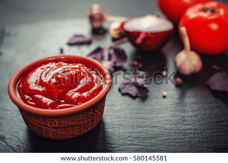 Hungarian tomato sauce with a mixture of peppers, cumin, basil, fenugreek against a black background with ingredients. close up, toned picture