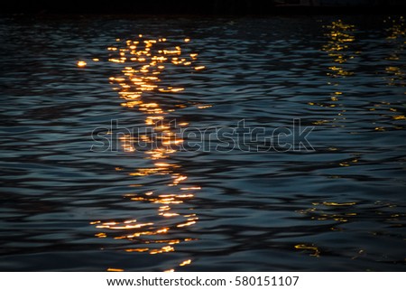 The reflection of light on water at night.