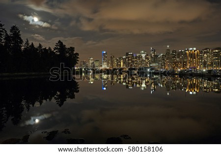 Skyline of Vancouver, British Columbia illuminated at night with Stanley Park and moon