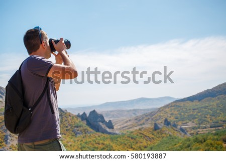Guy photographing mountain in summer