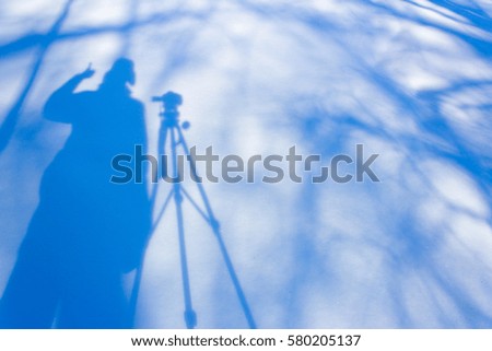 shadow photographer with a tripod in the snow in the winter frosty day