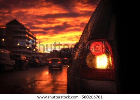 Tail light of the car against the background of the street lit with light before sunset reflected from bright clouds.