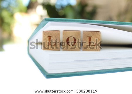 Read Between the lines. Concept  Internet lingo LOL. Laugh Out Loud   Research and learn. Wooden tiles between pages of a book. Stock photo.  White space for your own info or logo