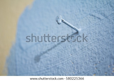 Blue painted nail stuck to a wall