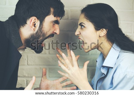 Young couple yelling at each other in studio Royalty-Free Stock Photo #580230316