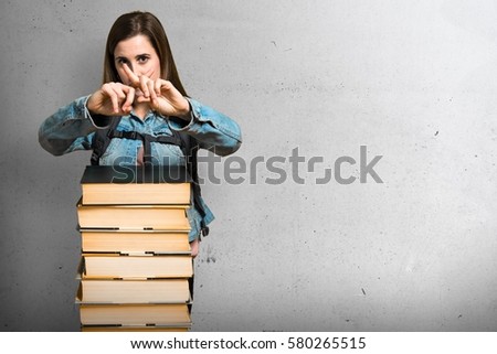Teen student girl with a lot of books and making NO gesture