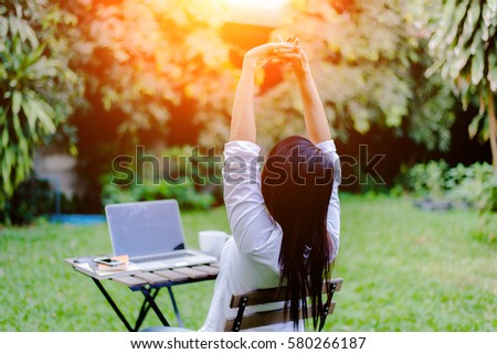 young business woman stretching hands while working at outdoor cafe