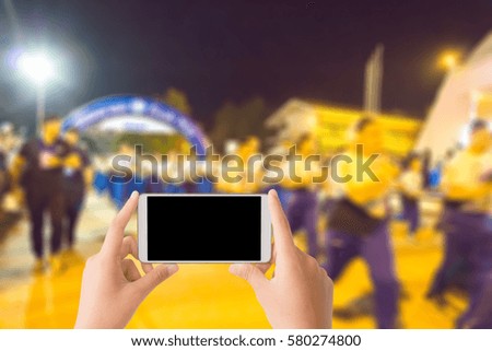 woman use mobile phone and blurred image of people in marathon racing at the start point