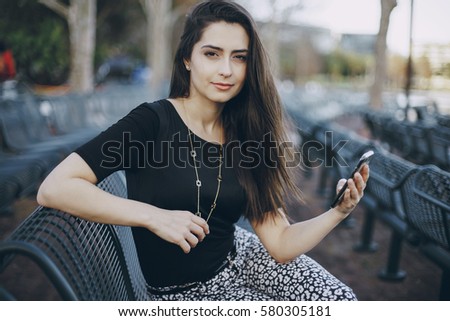 beautiful girl posing in black blouse sitting on the bench