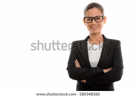 Studio shot of young happy businesswoman smiling while wearing eyeglasses with arms crossed