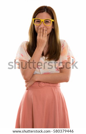 Studio shot of happy young beautiful woman smiling and giggling while covering mouth