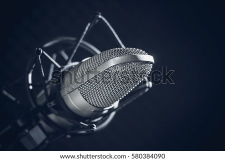 Microphone and audio console in holder, isolated on dark background in recording studio. Toned image