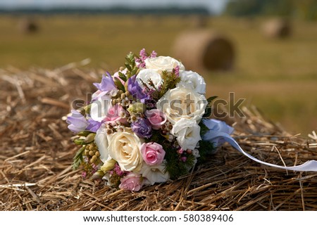 wedding bouquet of white and pink flowers on a stack of hay 