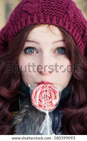 Redhead girl holding a lollipop in hand