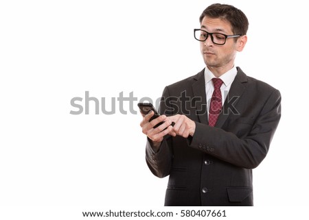 Studio shot of young businessman wearing eyeglasses while using mobile phone
