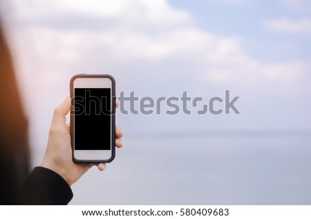 Copy space of woman hand using smart phone take photograph at beach background. Travel adventure and summer holiday concept. Shallow depth of field. Vintage tone filter color style.