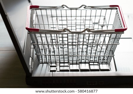 Shopping basket on laptop buying online abstract background concept