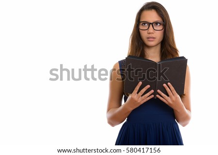 Studio shot of young beautiful woman wearing eyeglasses while holding book and thinking