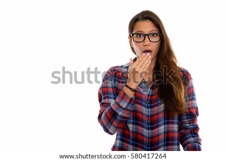 Studio shot of young beautiful woman looking surprised while covering mouth