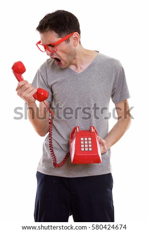 Studio shot of angry young man shouting at old telephone
