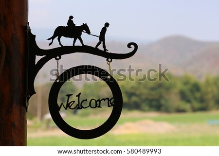 welcome sing with a horse and mountain for background in a farm