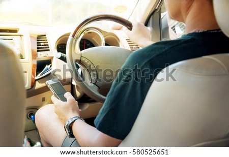 Asian man using a smartphone while driving. Car driver use gps mobile app for traveling. Focus on hand holding cellphone.