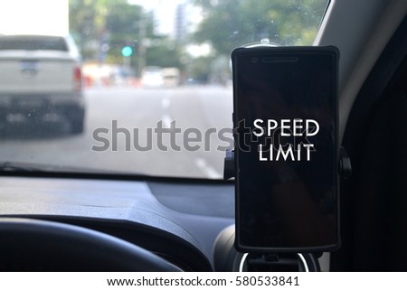 Speed limit written on a mobile phone attached to a holder in a car