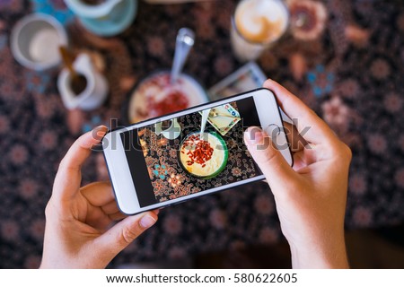 Hands with the phone close-up pictures of food. Breakfast, homemade oatmeal with fruit and goji berries. Royalty-Free Stock Photo #580622605