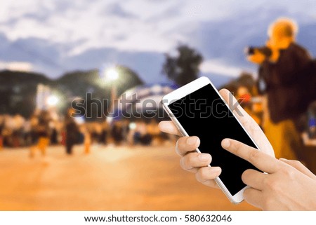 woman use mobile phone and blurred image of people in the marathon racing at the finished point