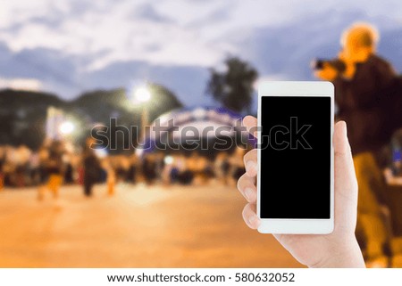 woman use mobile phone and blurred image of people in the marathon racing at the finished point