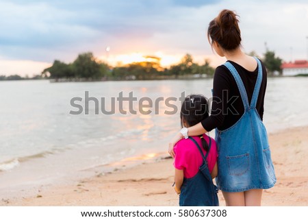 Mother and daughter standing looking Nature sunset The lake.
