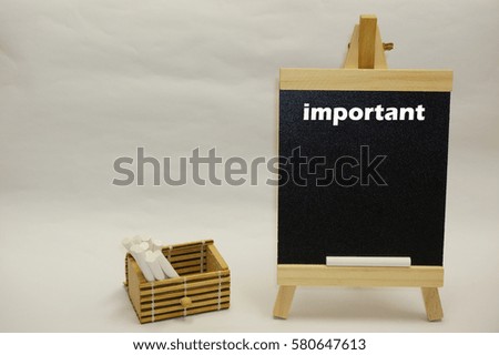 "Important" word written on mini chalkboard and white chalks inside wooden box case isolated over white background