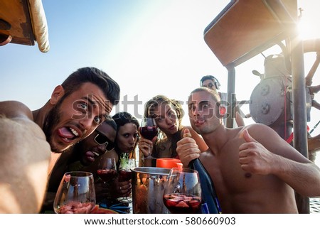 Happy friends taking selfie photo with mobile phone camera in boat party - Young people having fun in ibiza drinking champagne sangria - Summer vacation concept - Warm filter