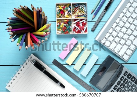 Office supplies and empty note pad on blue background, top view