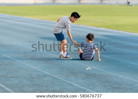 Young Asian boy running on blue track in the stadium during day time to practice himself. Royalty-Free Stock Photo #580676737