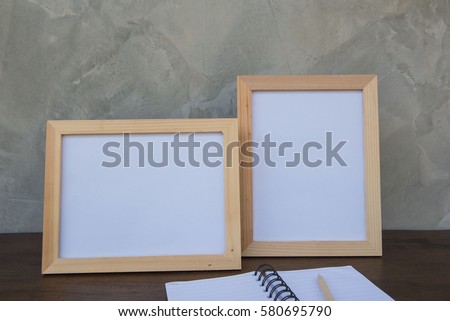 Two photo Frame on a wooden table and book on Gray wall background .