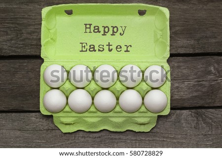 Green carton of organic eggs on wooden background. Top view.