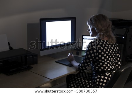 Overtime in the office. A young woman working at the computer late at night