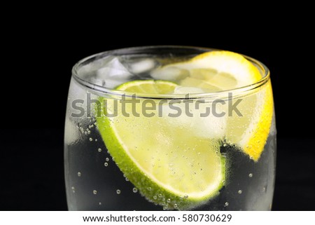 Mineral water in the glass with ice cubes, lime and lemon slices