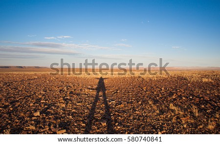 Fun silhouetted figure striking a pose against the red sand earth in the Namib desert, Namibia