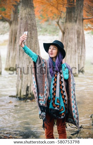 The girl dressed in a poncho pictures of herself in a cypress grove
