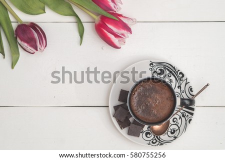 top view of coffee mug, candle and tulips to the holiday "international women's day" on white boards