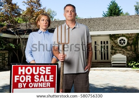 Mature couple standing outside newly bought property in style of American Gothic