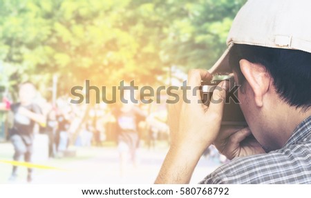 Man holding film camera ready to take photo over sport competition background
