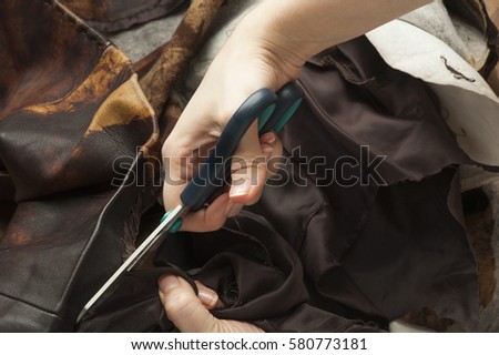 Tailor produces cutting brown leather for the manufacture of products.