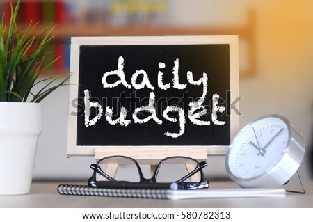 concept of coffee cup with stand board on blurred modern office background with DAILY BUDGET words. tone image