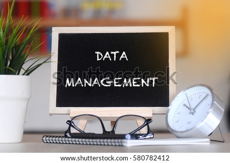 concept of coffee cup with stand board on blurred modern office background with DATA MANAGEMENT words. tone image