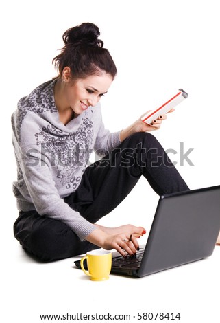 Lovely cheerful brunette sitting on the floor and surfing with laptop over white