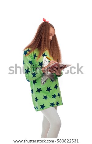 Young girl with long hair in a green tunic with a star with a notebook and pen for notes on a white background posing in the studio
