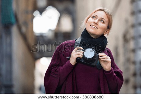 Young charming smiling woman looking curious and taking pictures outdoors